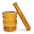 A wooden mortar and pestle set on a clean white background. The mortar is made of smooth, polished wood with a rounded, ribbed design and sits on the left, while the pestle leans diagonally against the right side of the mortar.