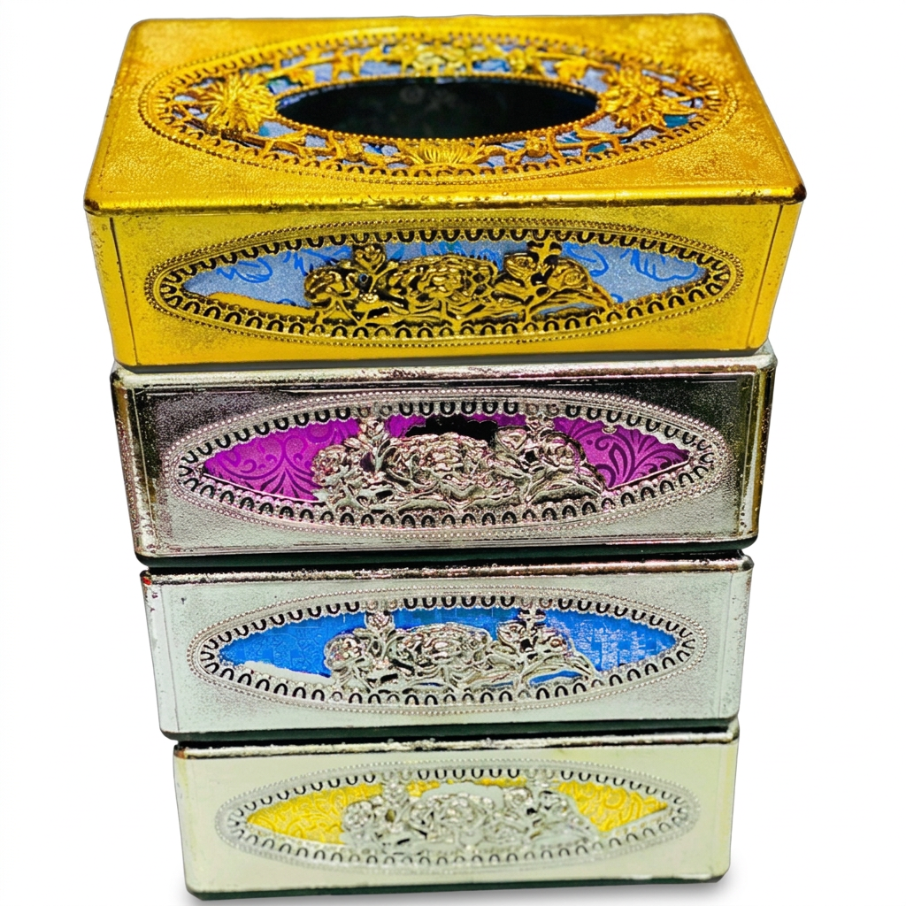 A stack of four decorative tissue boxes with ornate metallic engravings and colorful oval panels. The top box is gold with blue and gold detailing, the next is silver with purple and silver detailing, the third is silver with blue and silver detailing, and the bottom box is cream with gold and silver detailing.